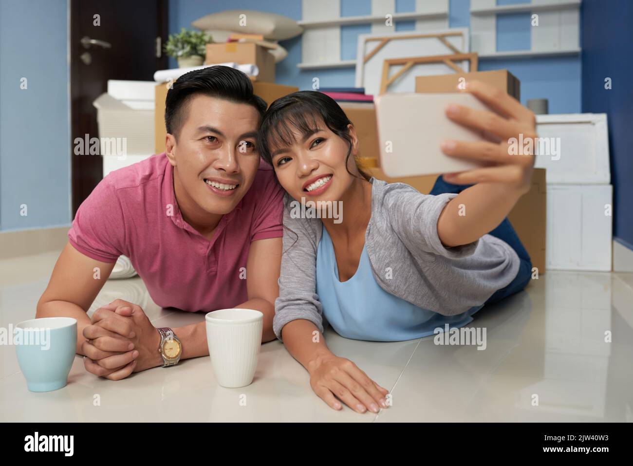 Young Asian couple taking selfie on smartphone and smiling happily ...