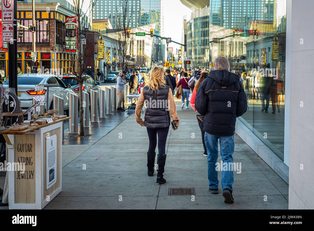 Tourists, a father and daughter, shot from the back, walk on the sidewalk in downtown Nashville, Tennessee. Stock Photo
