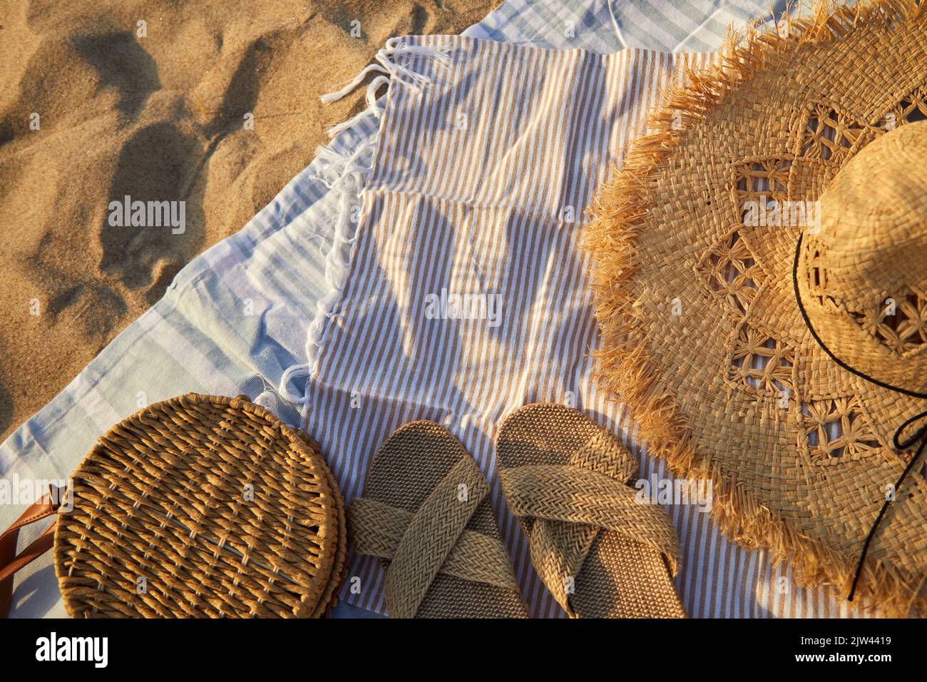 Top view of beach accessories. Straw hat, bag, flip flops on sand at ...