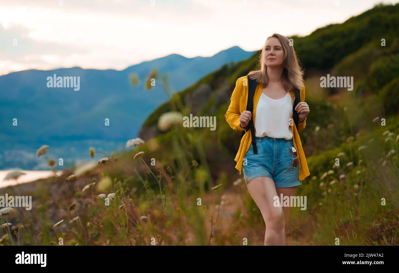 Woman tourist with backpack walking in mountains. Stock Photo