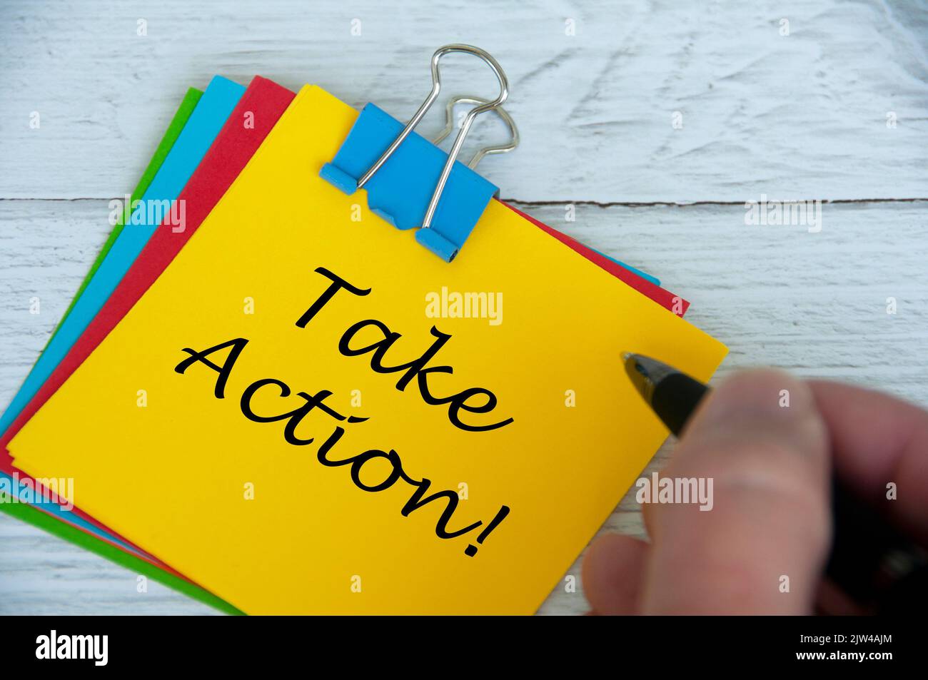 Motivational and inspirational quotes text on notepad - Take Action. With hand holding pen. Stock Photo