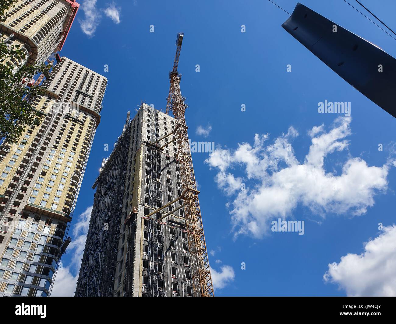 Modern process of skyscraper site construction or tall buildings on blue sky background. Perspective view from below. Industrial urban background. Mod Stock Photo