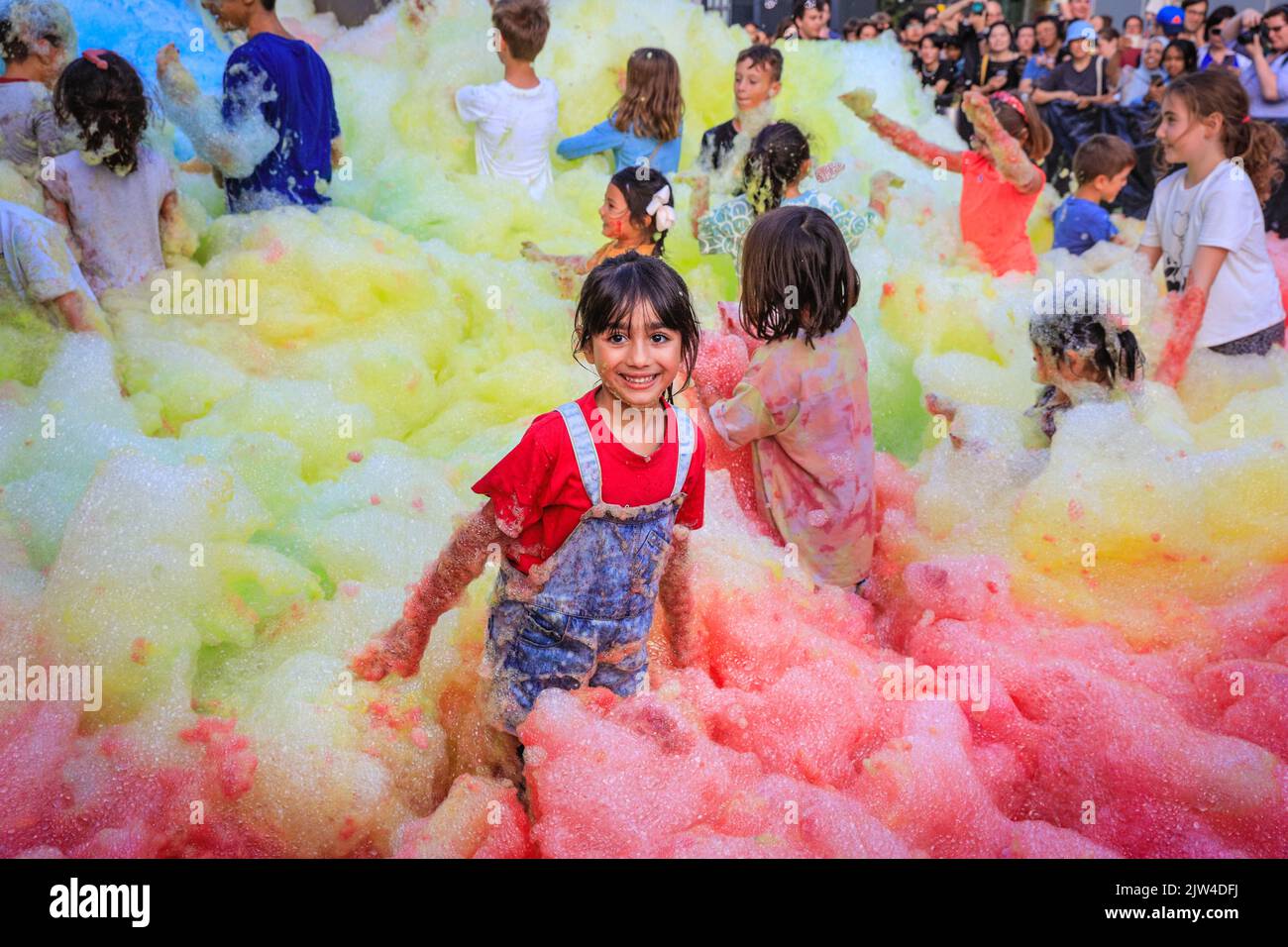 London, UK. 03rd Aug, 2022. Zahara, who is visiting the installation with her dad, loves jumping around in the foam. People interact with 'Island of Foam: Version XVIII', a colourful, constantly changing foam installation. The installation is a UK premiere from German artist Stephanie Lüning (who is operating the 'foam cannon' at the top of the stairs), transforming Greenwich Peninsula with mountains of rainbow coloured foam. Credit: Imageplotter/Alamy Live News Stock Photo