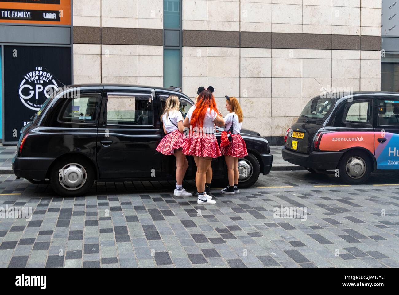 Micky Mouse teenage girls explaining a trip to a taxi driver in Liverpool Stock Photo
