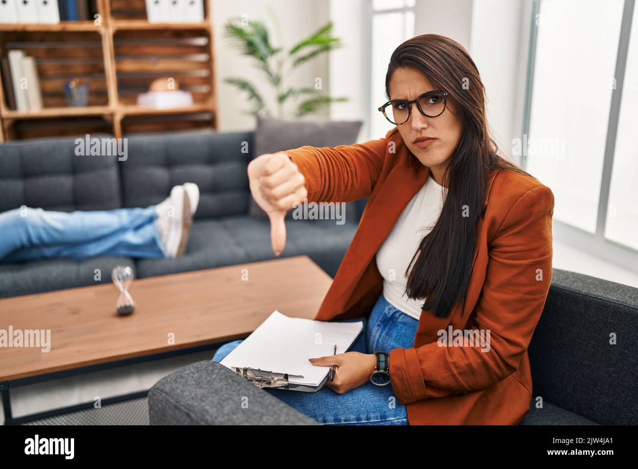 Young hispanic woman working as psychology counselor looking unhappy ...