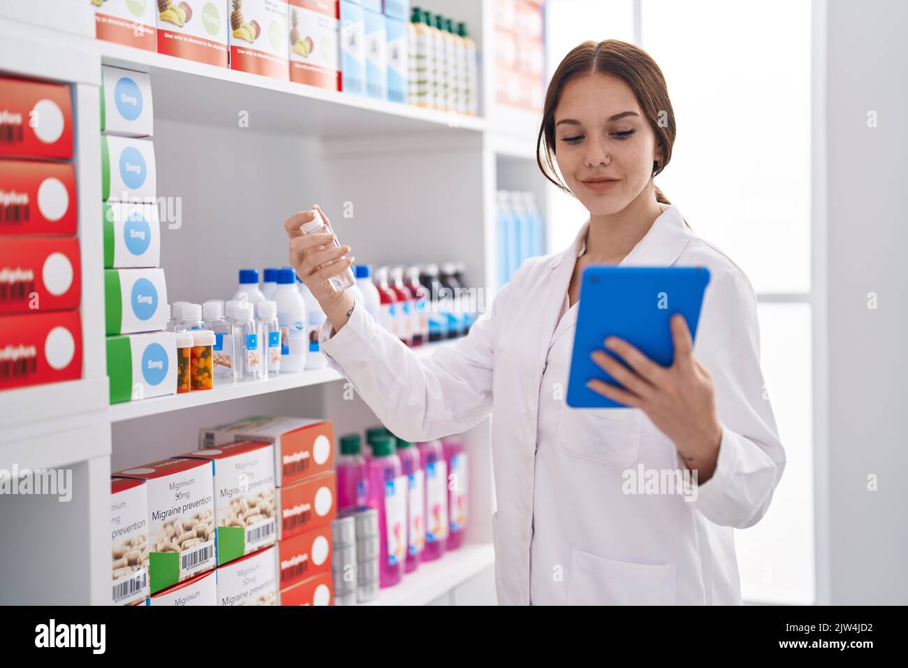 Young woman pharmacist using touchpad holding bottle at pharmacy Stock ...