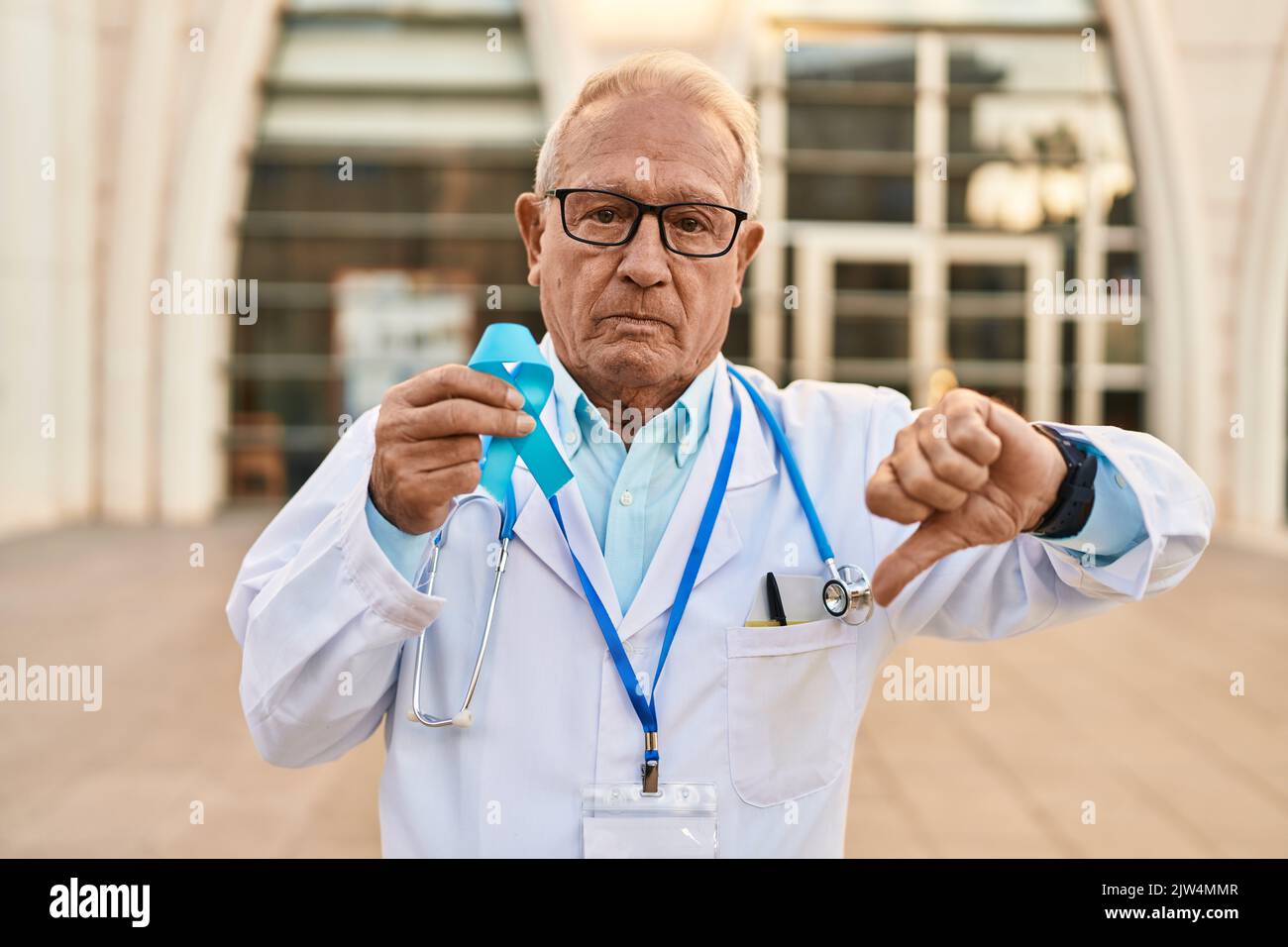 Senior doctor with grey hair holding blue ribbon with angry face ...