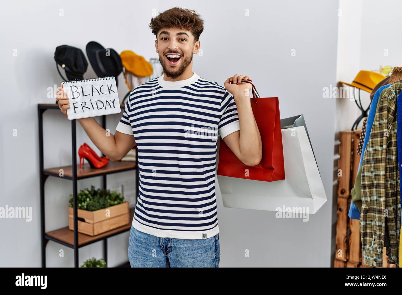 Young arab man customer holding shopping bags and black friday banner ...