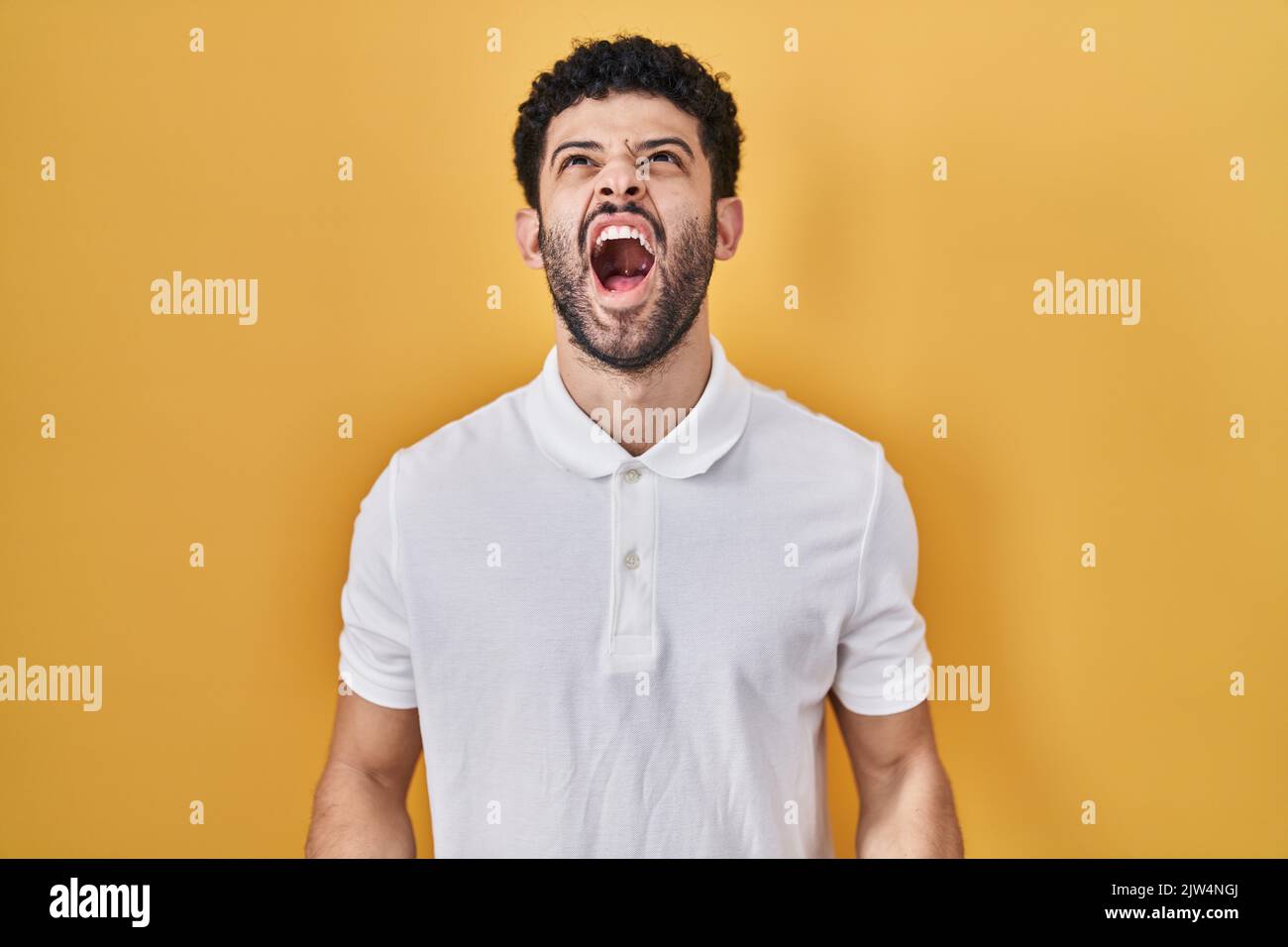 Arab man standing over yellow background angry and mad screaming frustrated and furious
