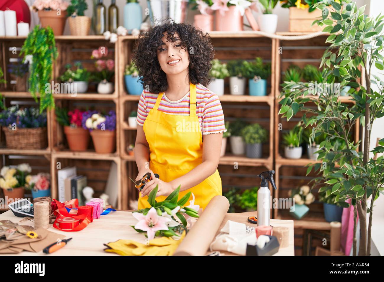 Young middle eastern woman florist make bouquet of flowers at florist ...