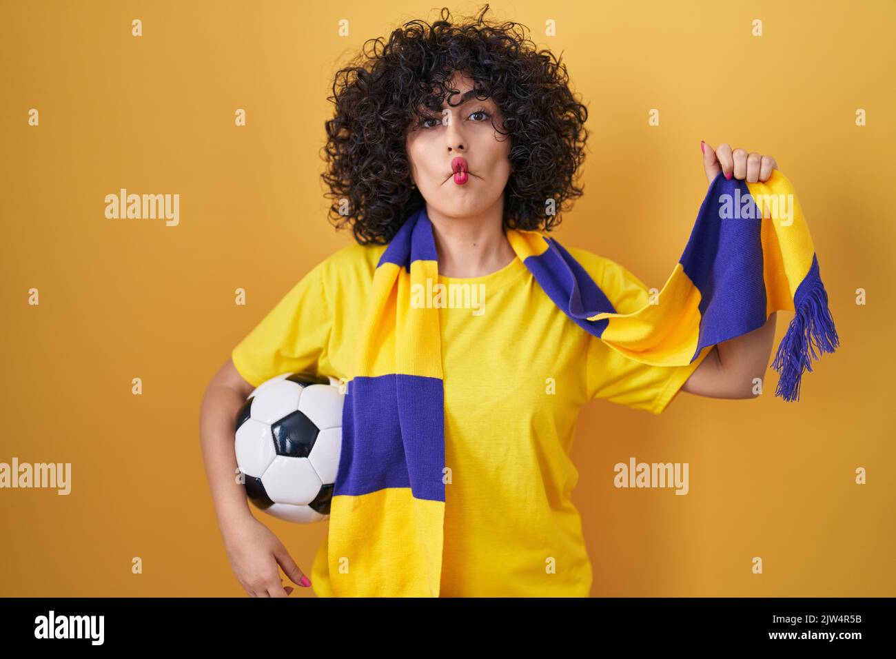 Young brunette woman with curly hair football hooligan holding ball ...