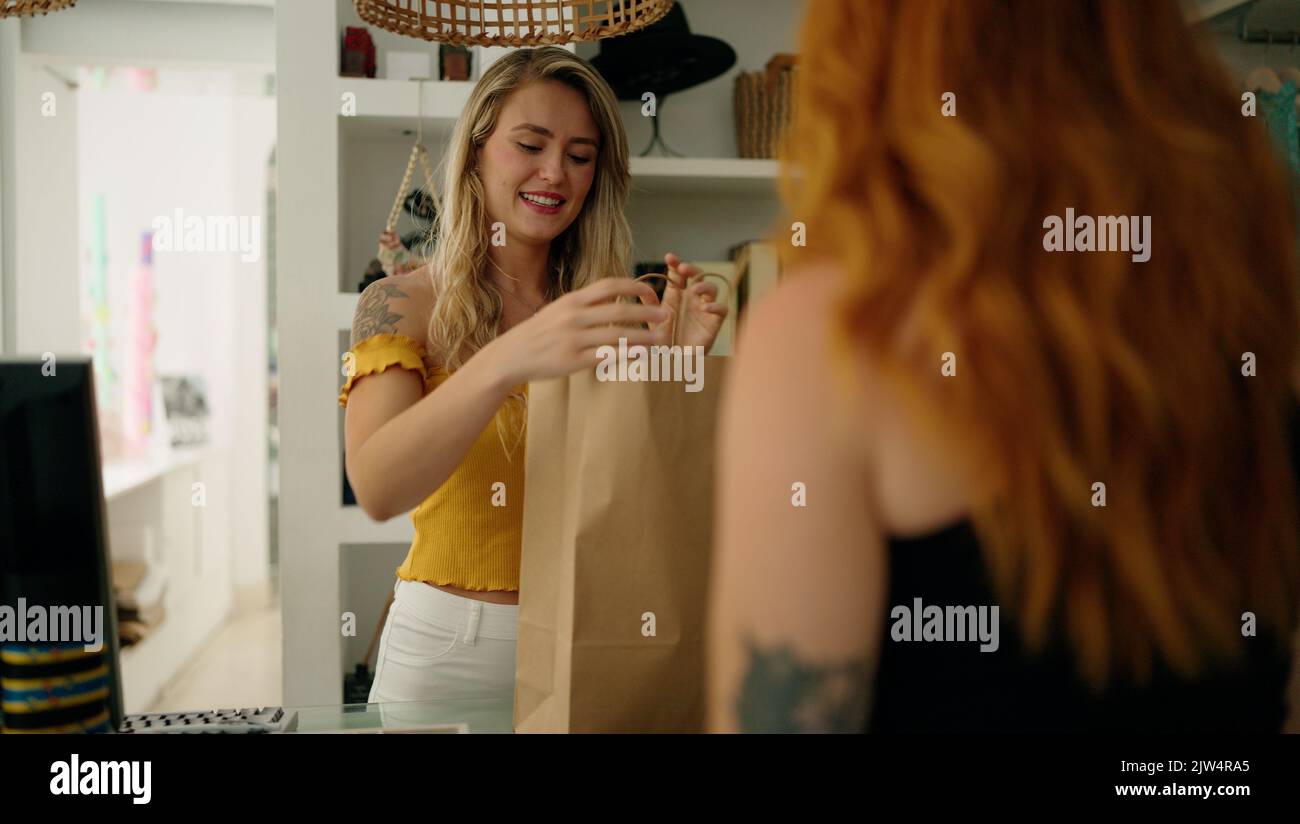 Two women customer buying at clothing store Stock Photo - Alamy