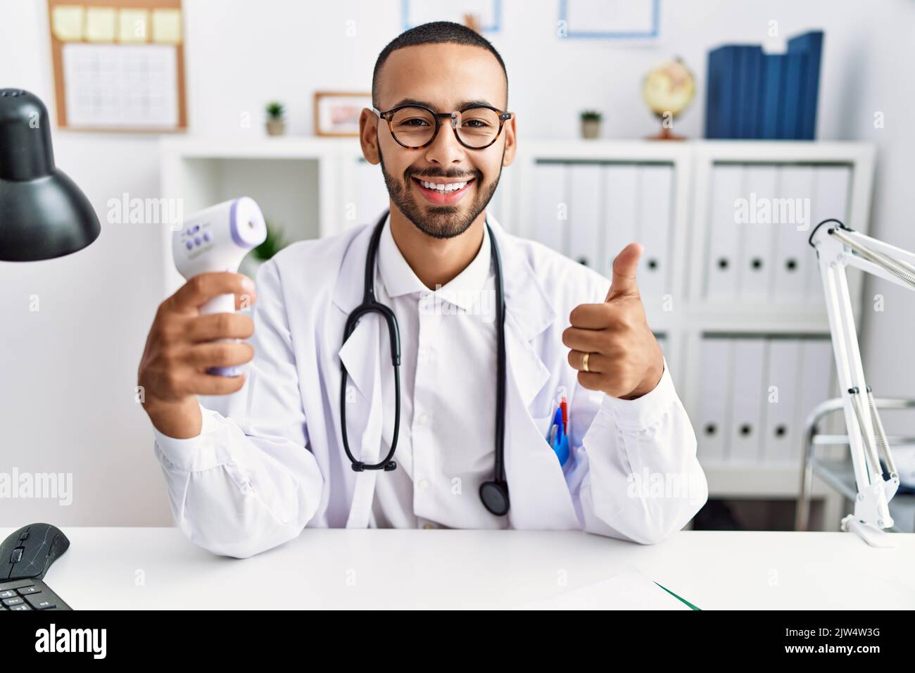 African american doctor man holding thermometer at the clinic smiling ...