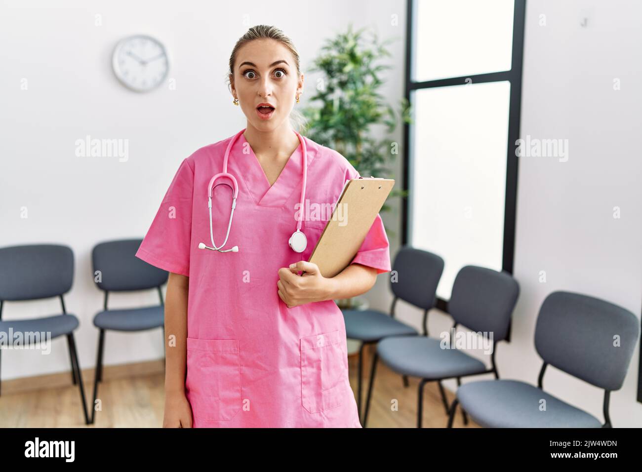 Young Nurse Woman At Medical Clinic Waiting Room Scared And Amazed With