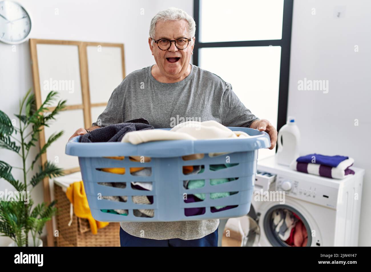 Senior caucasian man holding detergent bottle at laundry room smiling