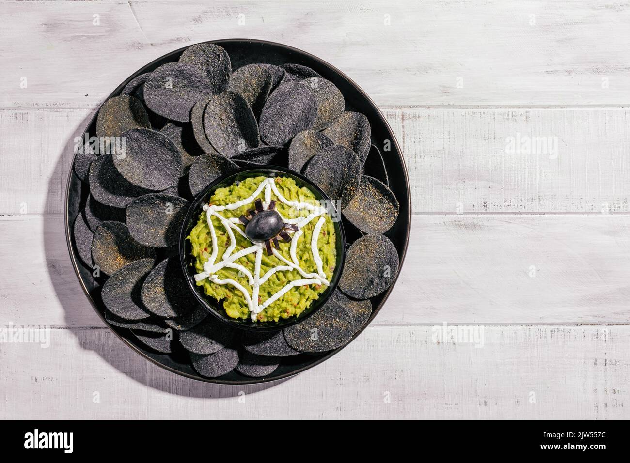 Spooky Halloween black potato chips with guacamole dip Stock Photo Alamy