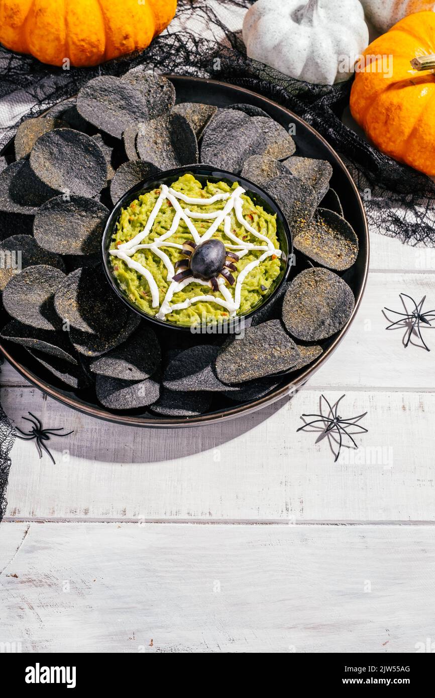 Spooky Halloween black potato chips with guacamole dip Stock Photo Alamy