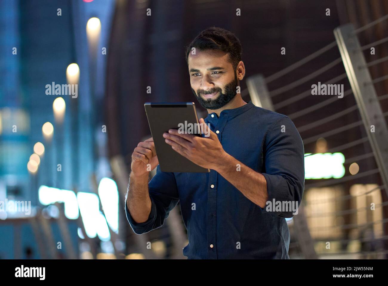 Professional indian business man using digital tablet outdoors in night city. Stock Photo