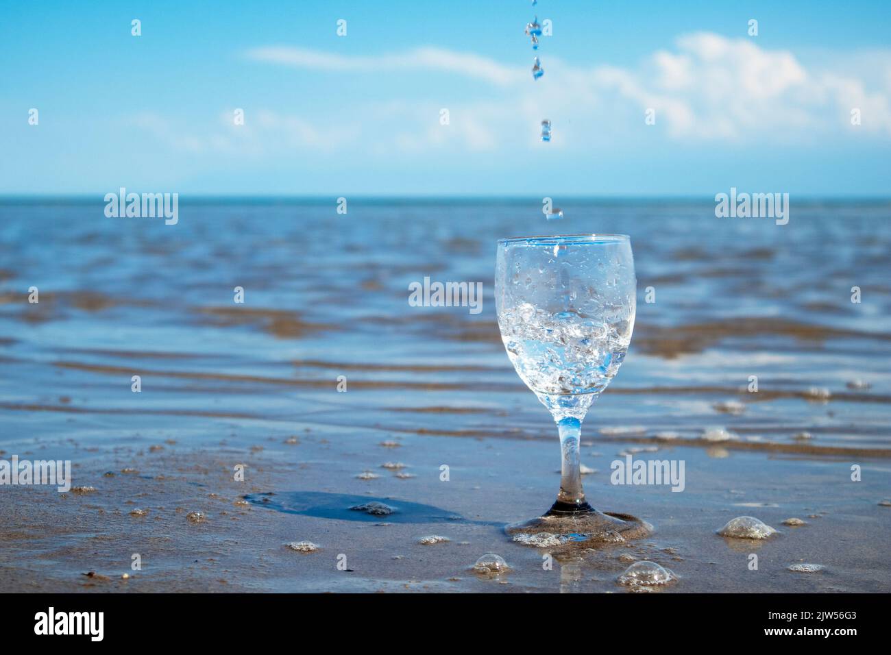 water pours into a glass against the background of the sea. clean water