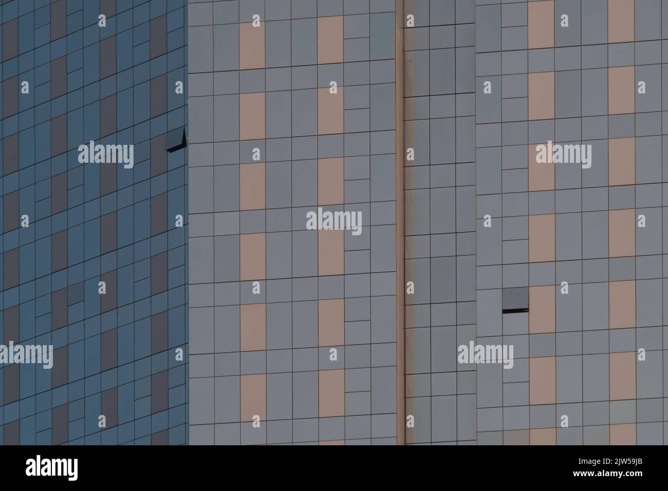 Closeup of glass building exterior with two windows open. Panes come