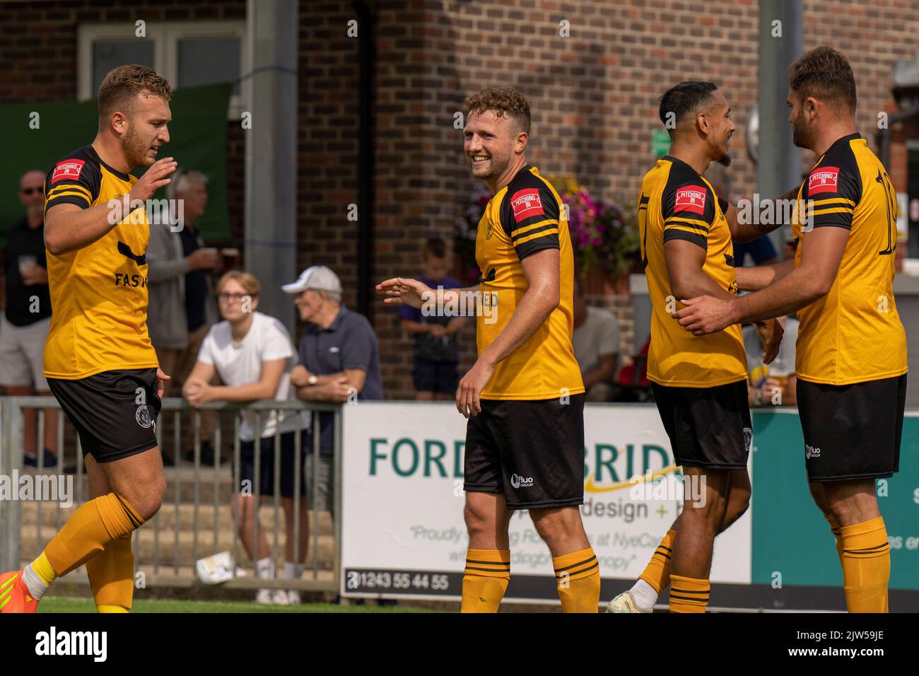 Football match action from Bognor Regis Town FC vs Cray Wanderers - FA Cup game. Four players smile and congratulate each other after scoring a goal Stock Photo