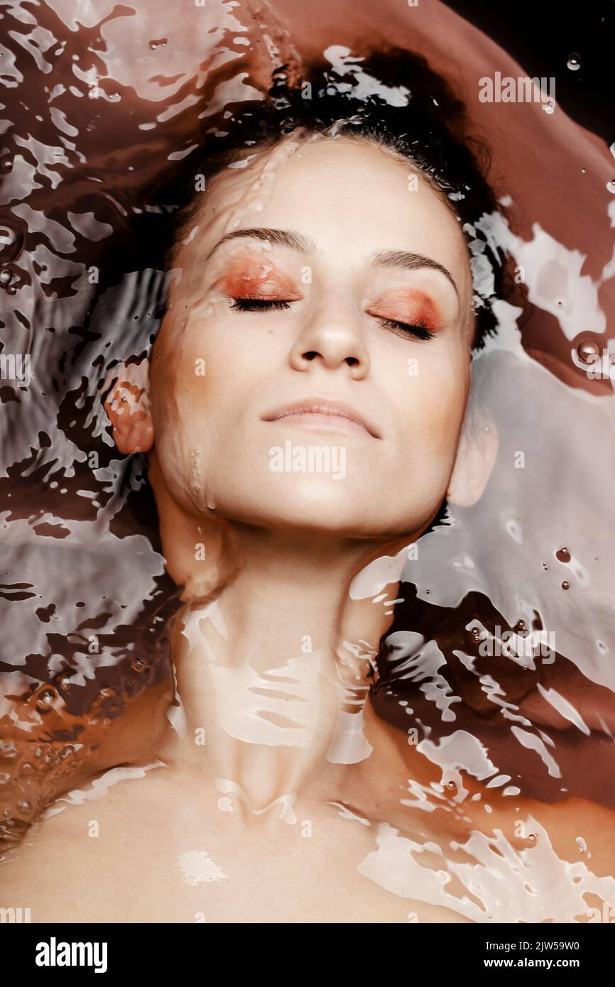 Underwater beauty portrait of a beautiful caucasian girl. Eyes closed. Red colored water. Stock Photo