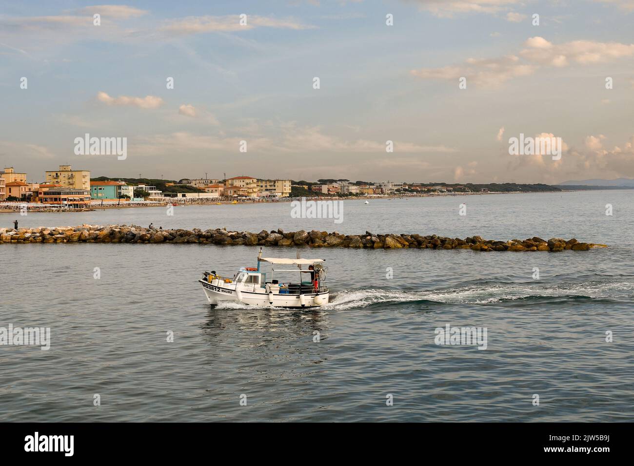 A small fishing boat entering in the harbor of San Vincenzo at sunset, Livorno, Tuscany, Italy Stock Photo