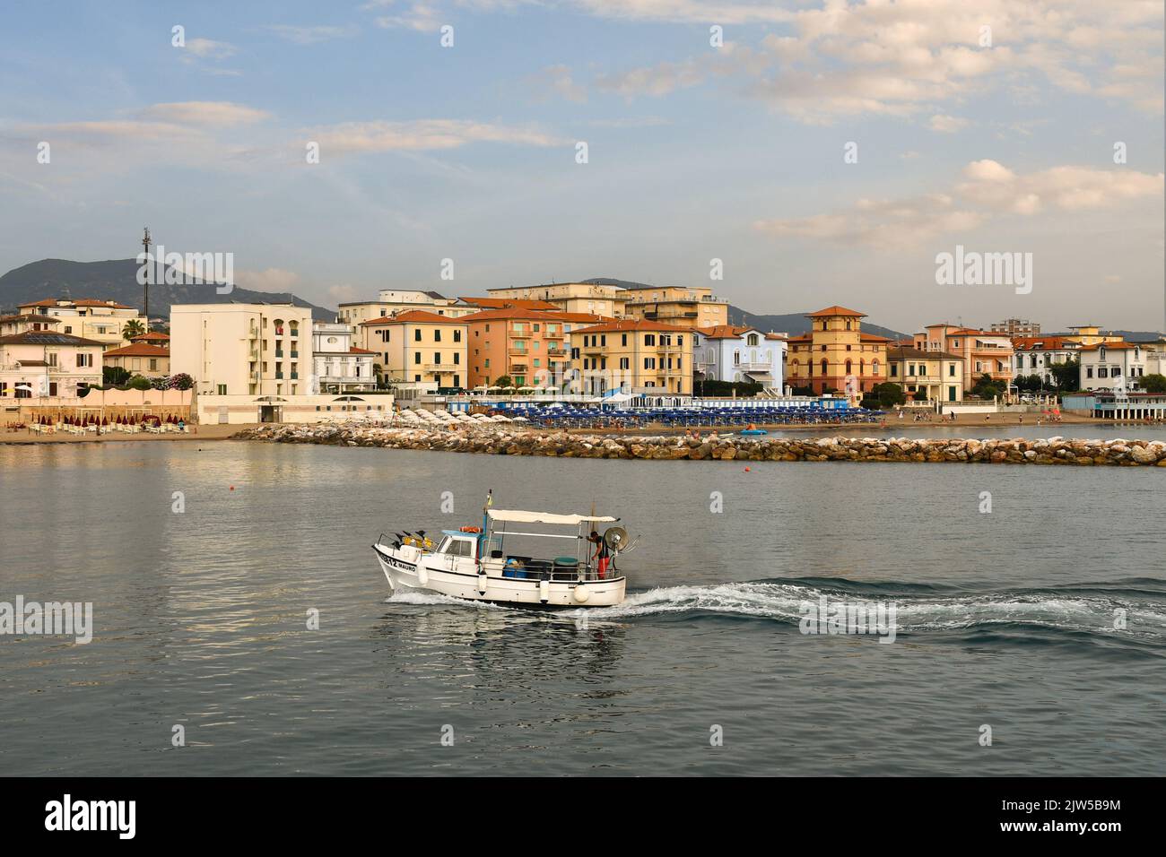 A small fishing boat entering in the harbor of San Vincenzo at sunset, Livorno, Tuscany, Italy Stock Photo