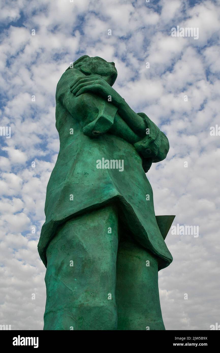 Low-angle view of the big bronze statue The Sailor in the harbour of the fishing village against clear blue sky, San Vincenzo, Livorno, Tuscany, Italy Stock Photo