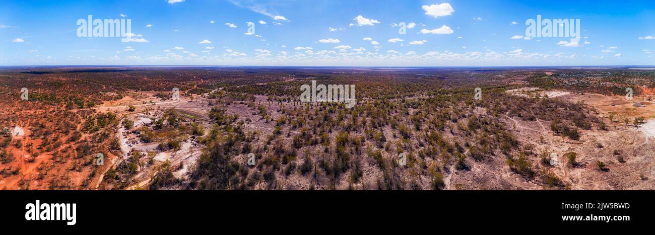 Opal mine shafts on red soil plains around Lightning Ridge regional town in NSW of Australia - aerial panorama. Stock Photo