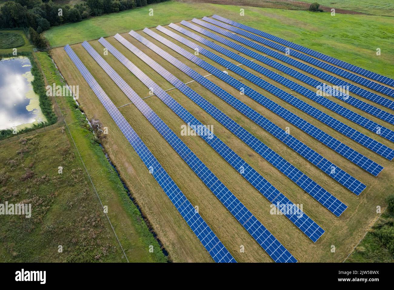 Aerial view of solar panels on a green grass field. Alternative energy source. Stock Photo