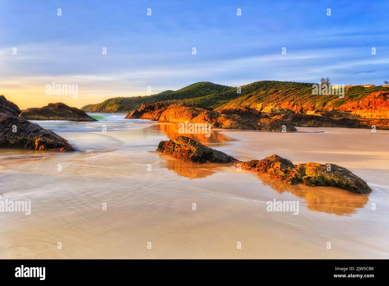 Clean sandy Burgess beach with scenic rocks at sunrise on Pacific coast in Forster town of Australia. Stock Photo
