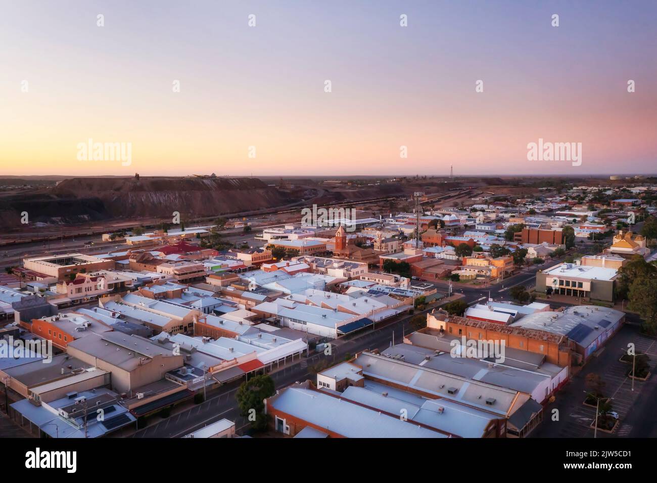 Line of lode old open pit silver mine in Broken Hill city of Outback Australia at sunrise in aerial cityscape. Stock Photo