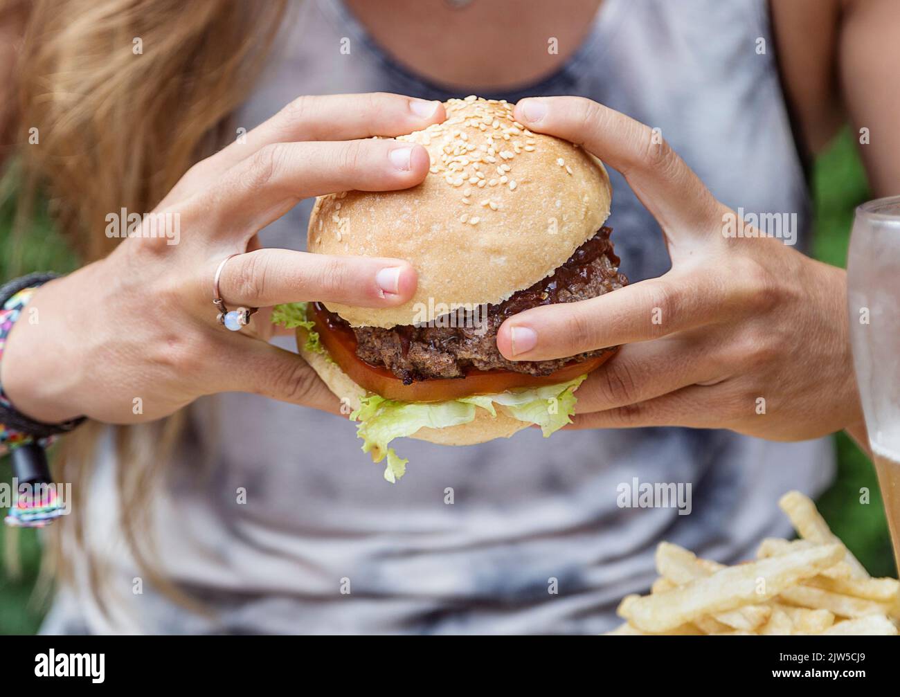 Hands holding a burger, on a restaurant table. Delicious and nutritious food. American style. Stock Photo