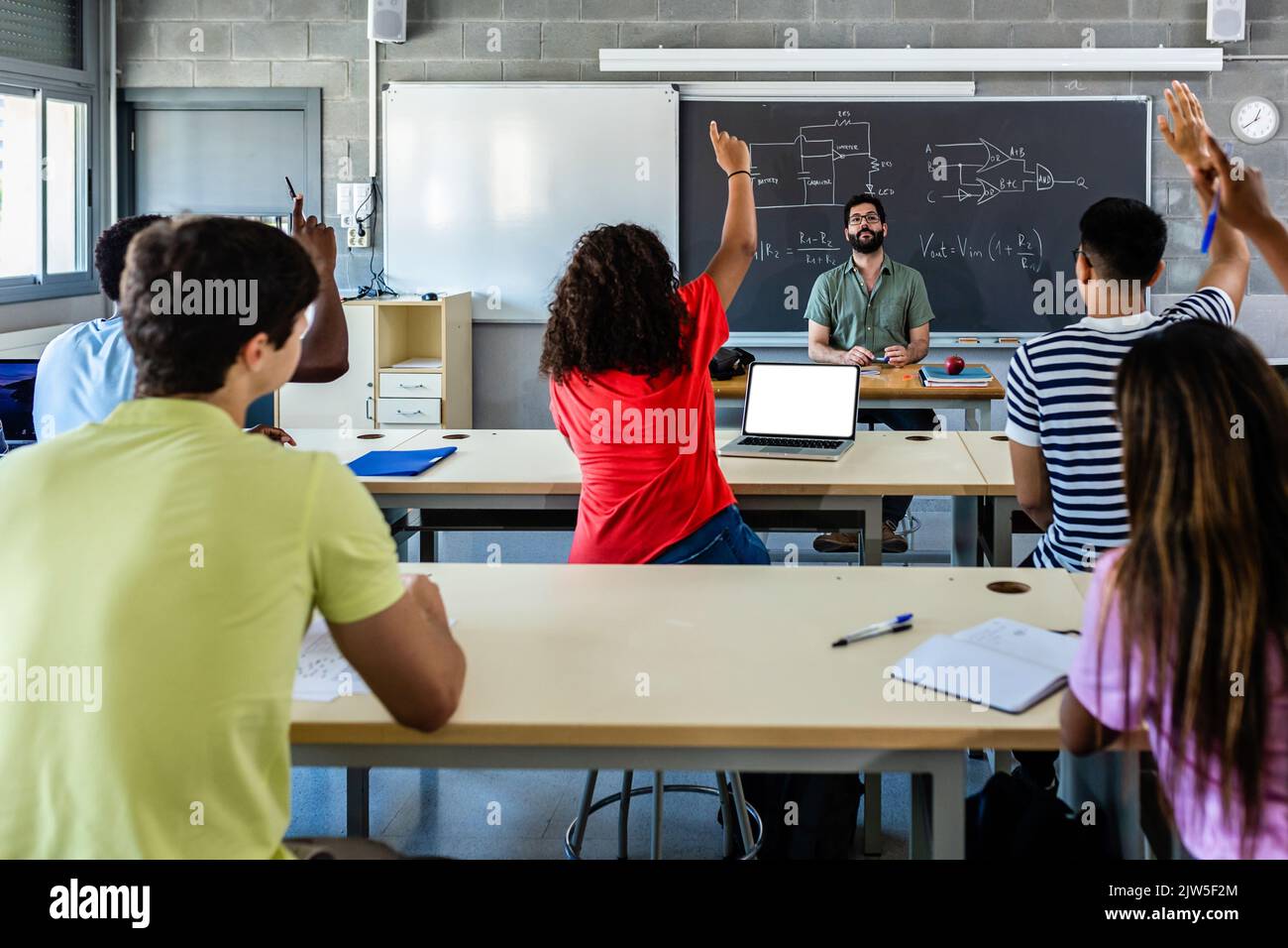 Group of young students raising hands in class on lecture Stock Photo