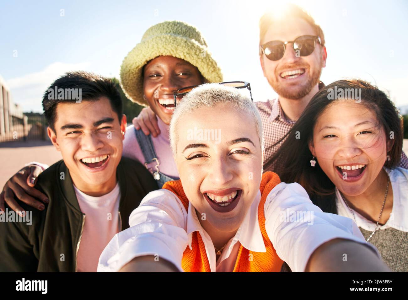 Smiling selfie of cheerful group of young people. Happy friends video call excited having fun. Interracial boys and girls taking picture looking at Stock Photo
