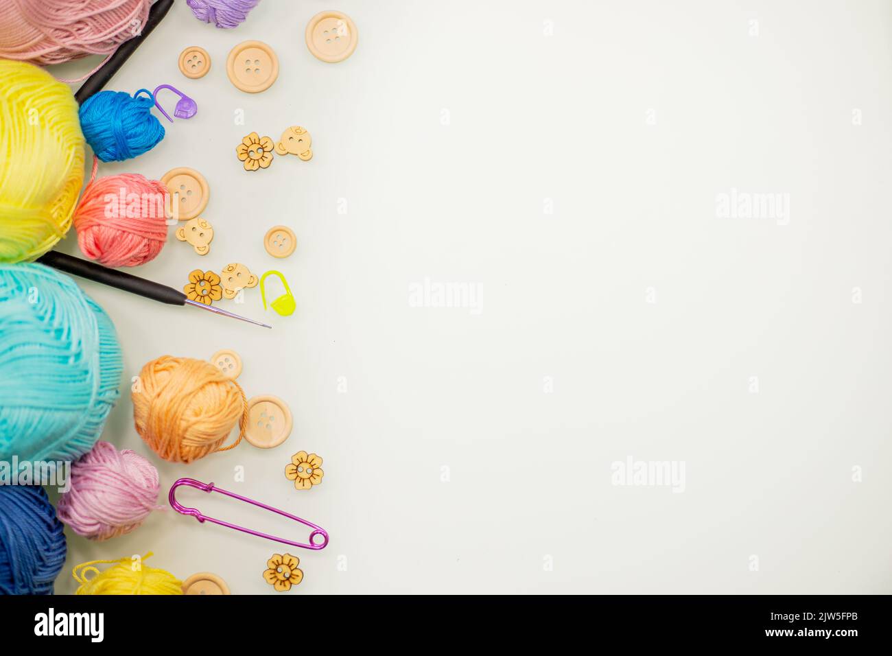 Flat lay composition with knitting threads and hook and buttons on white table, space for text, top view. Stock Photo