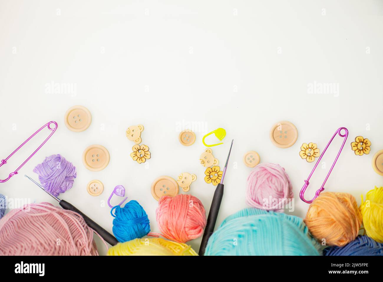 Flat lay composition with knitting threads and hook and buttons on white table, space for text, top view. Stock Photo