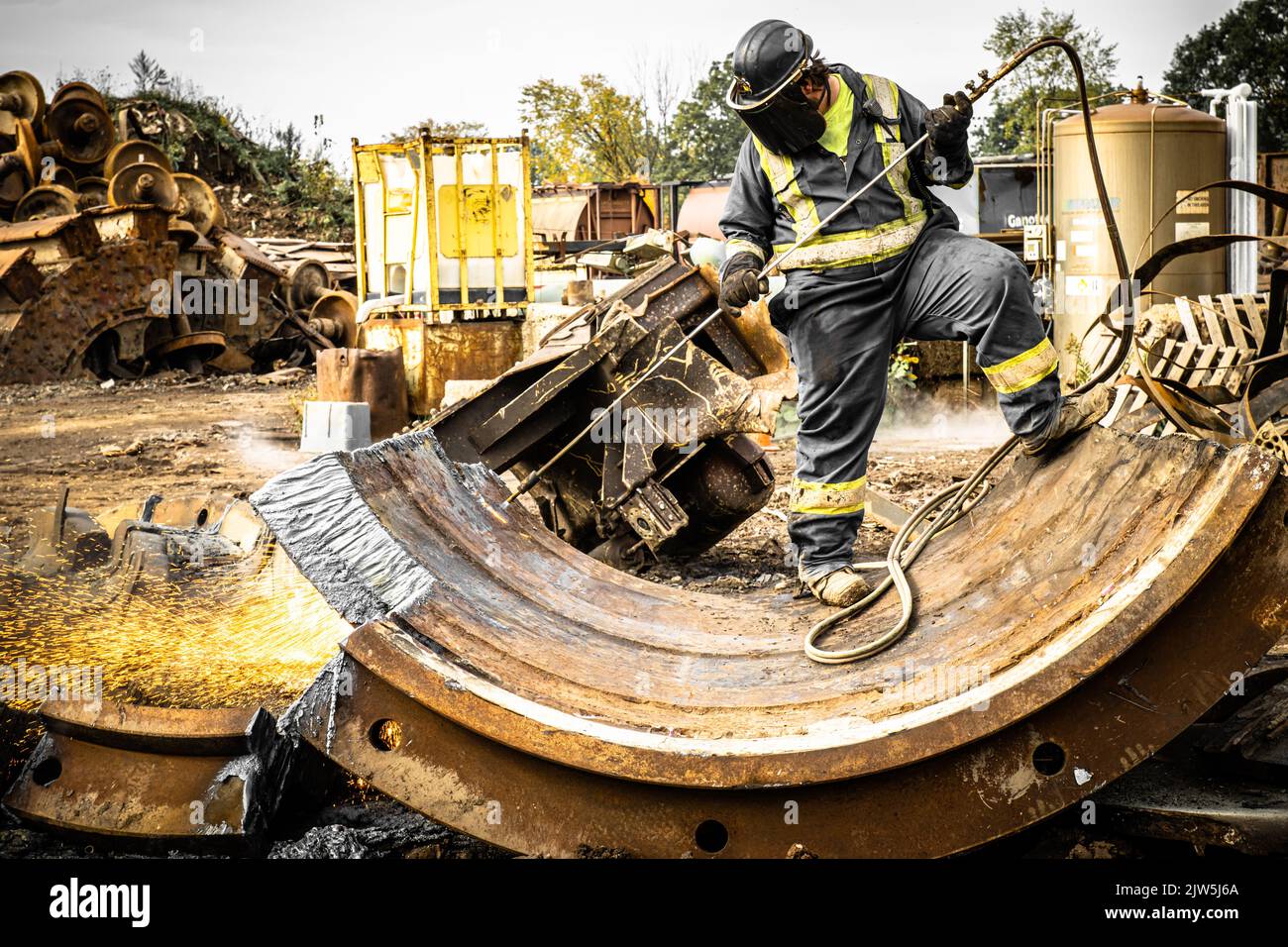 A man in a working uniform using a thermal torch dividing steel Stock