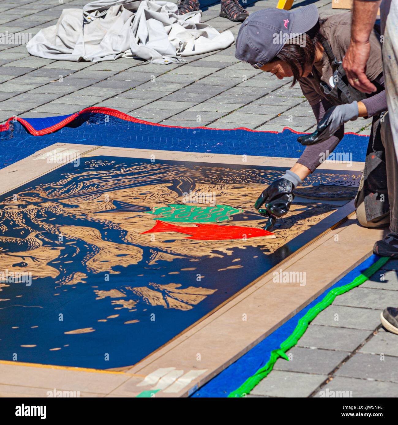 An artist adding coloured inserts to her very large woodblock at a Steveston demonstration in British Columbia Canada Stock Photo