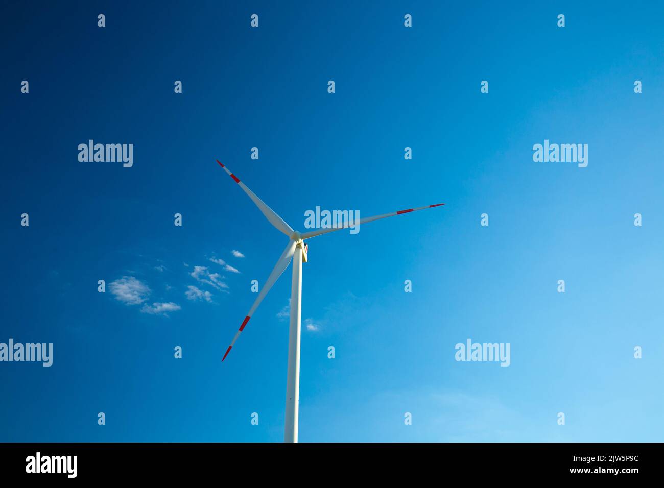 W ind generator on a blue sky background.Natural energy.Alternative natural energy source.Windmill renewable energy. Stock Photo
