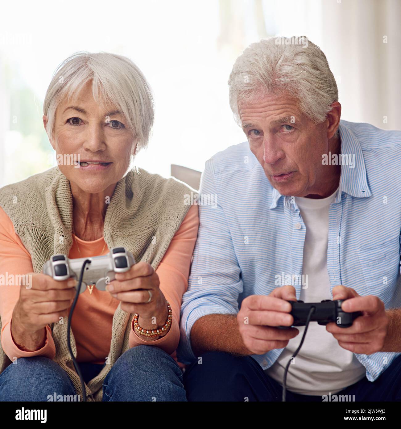 I know I can beat him this time...a senior couple playing video games. Stock Photo