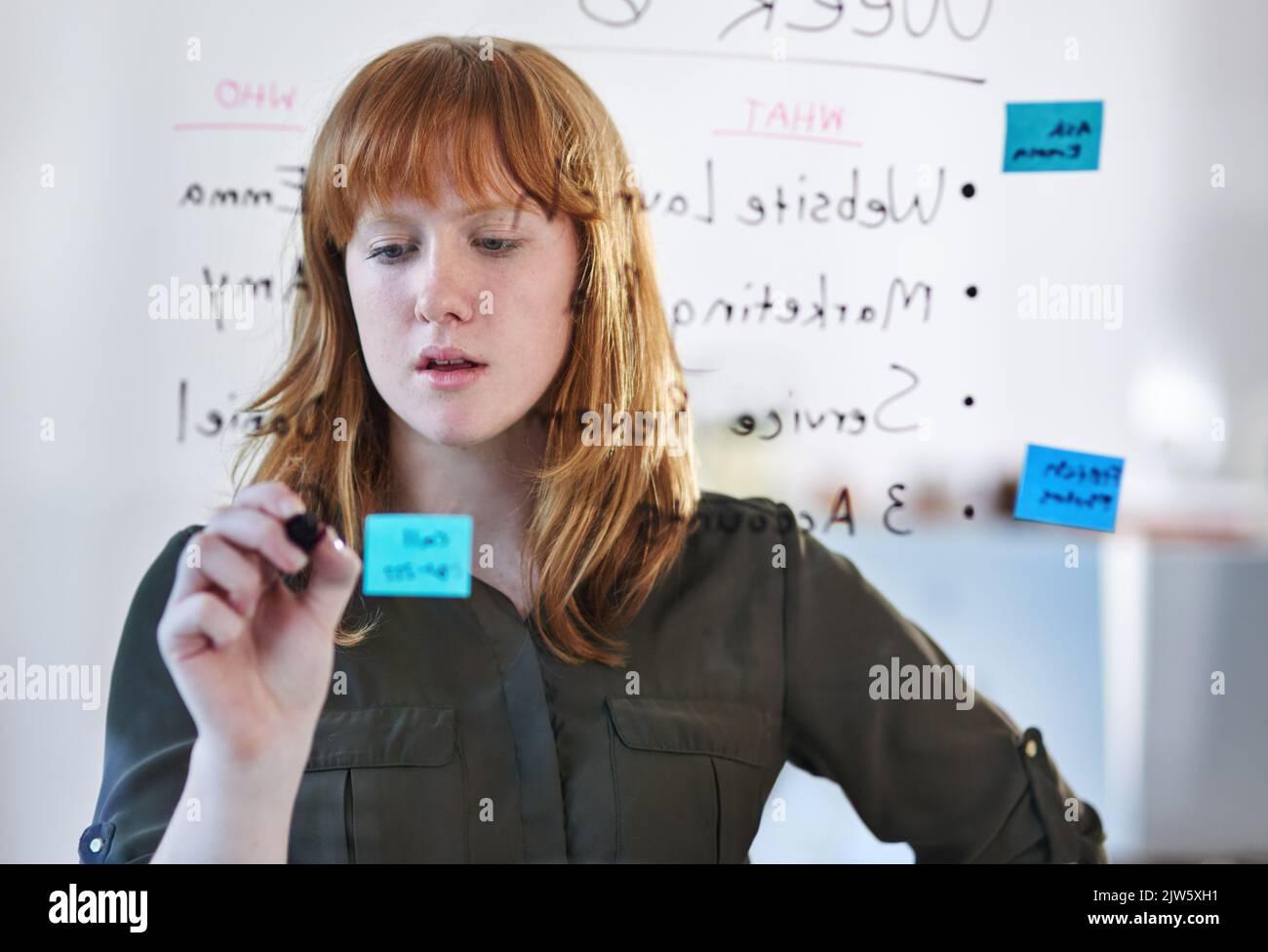 Planning on the pane. a young woman creating a plan on glass in a modern office. Stock Photo