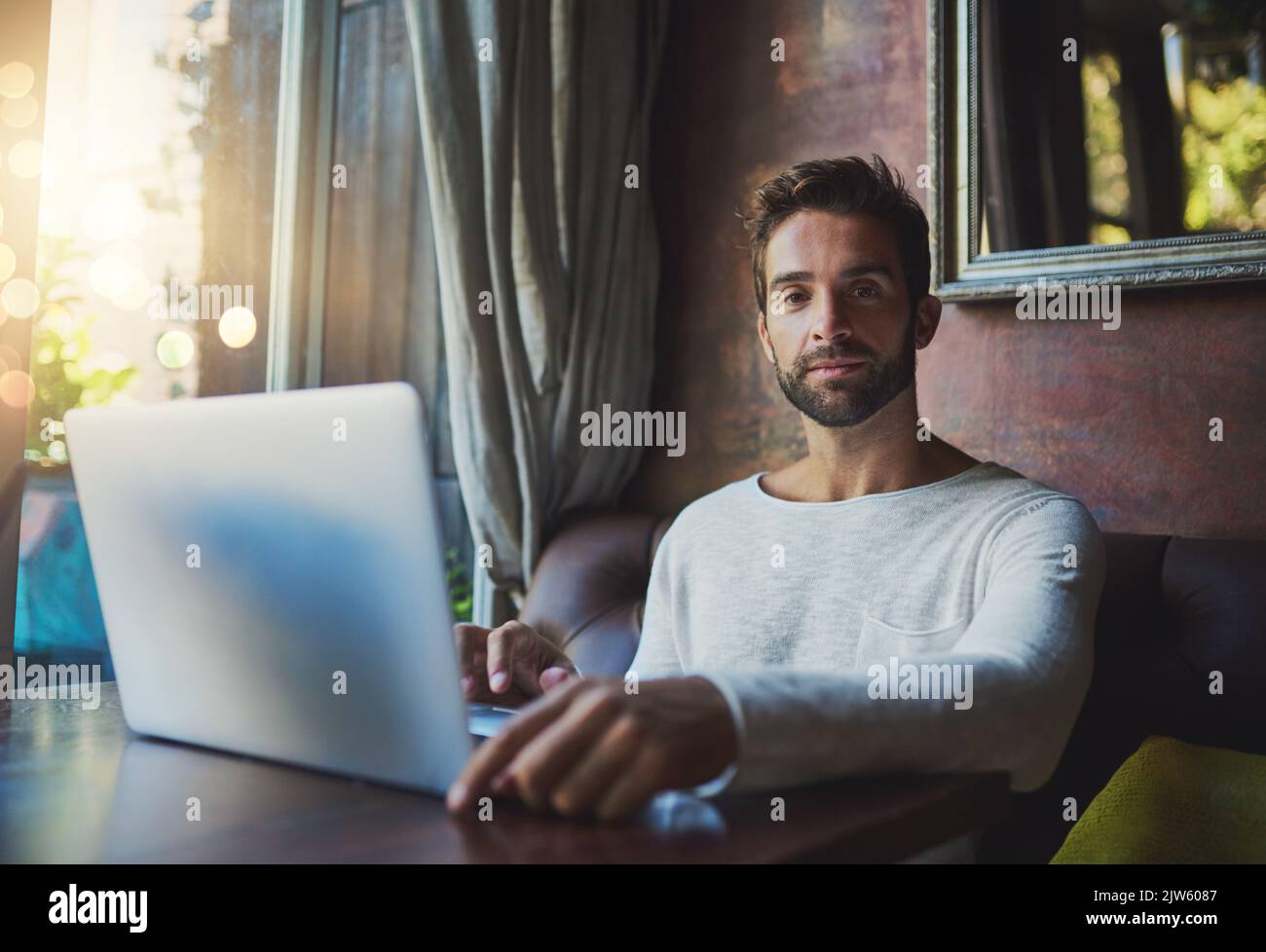 The best wifi is free wifi. Cropped portrait of a young man using his laptop in a coffee shop. Stock Photo