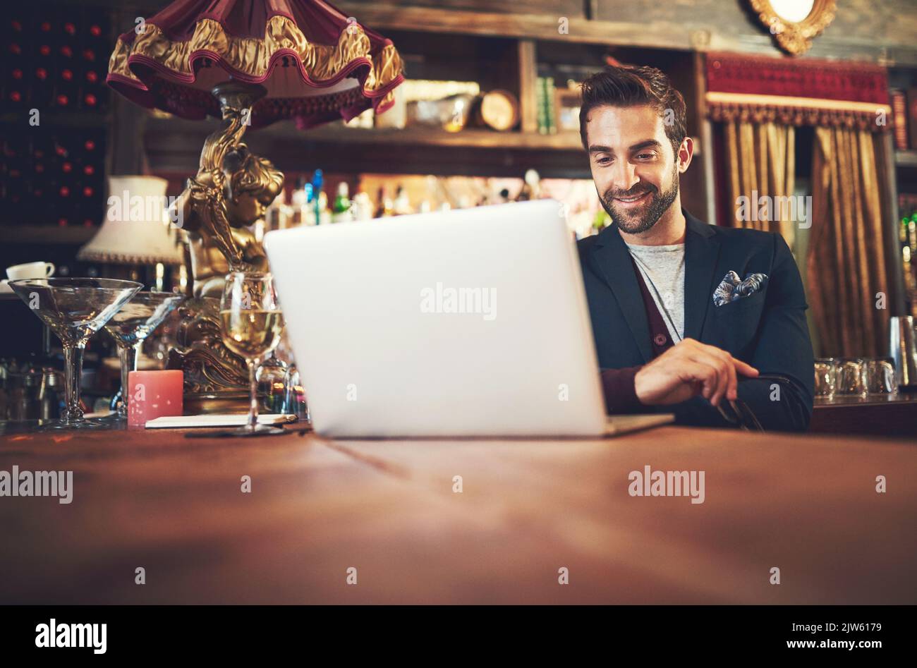 Blogging in the bar. a young man using his laptop while sitting in a bar. Stock Photo