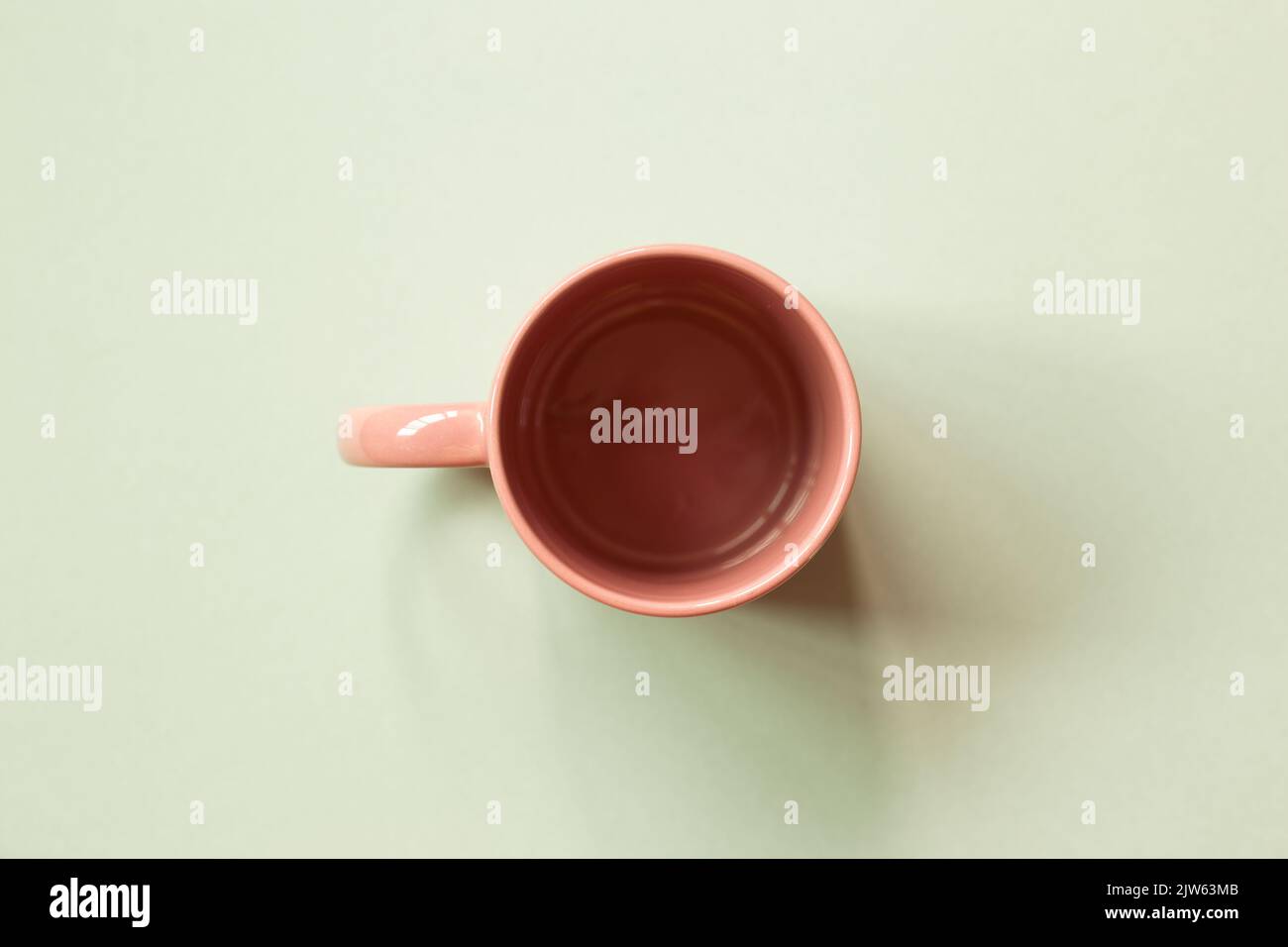 Pink mug cup on green background. copy space Stock Photo