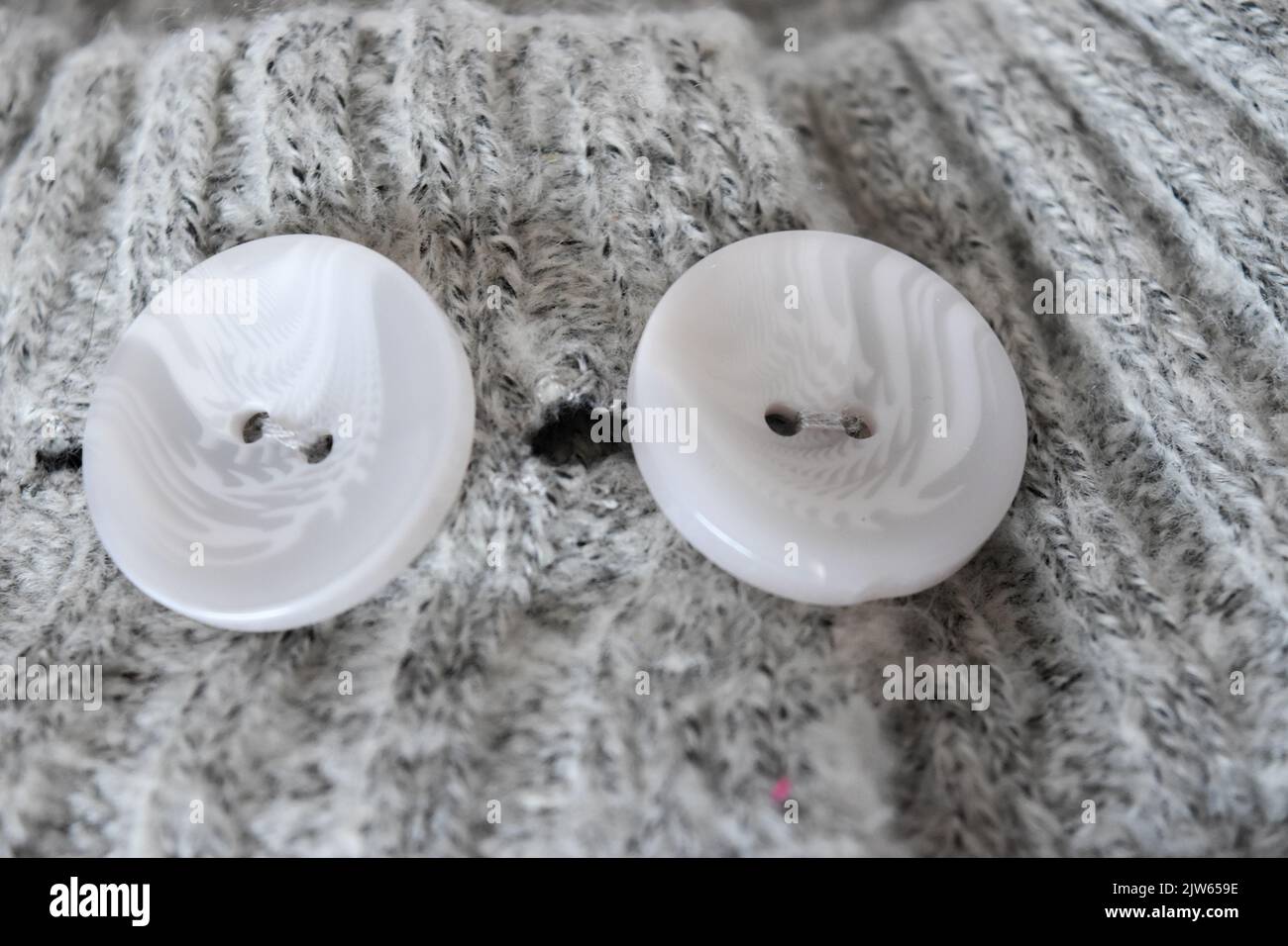 White plastic button on gray knitted fabric texture background Stock Photo