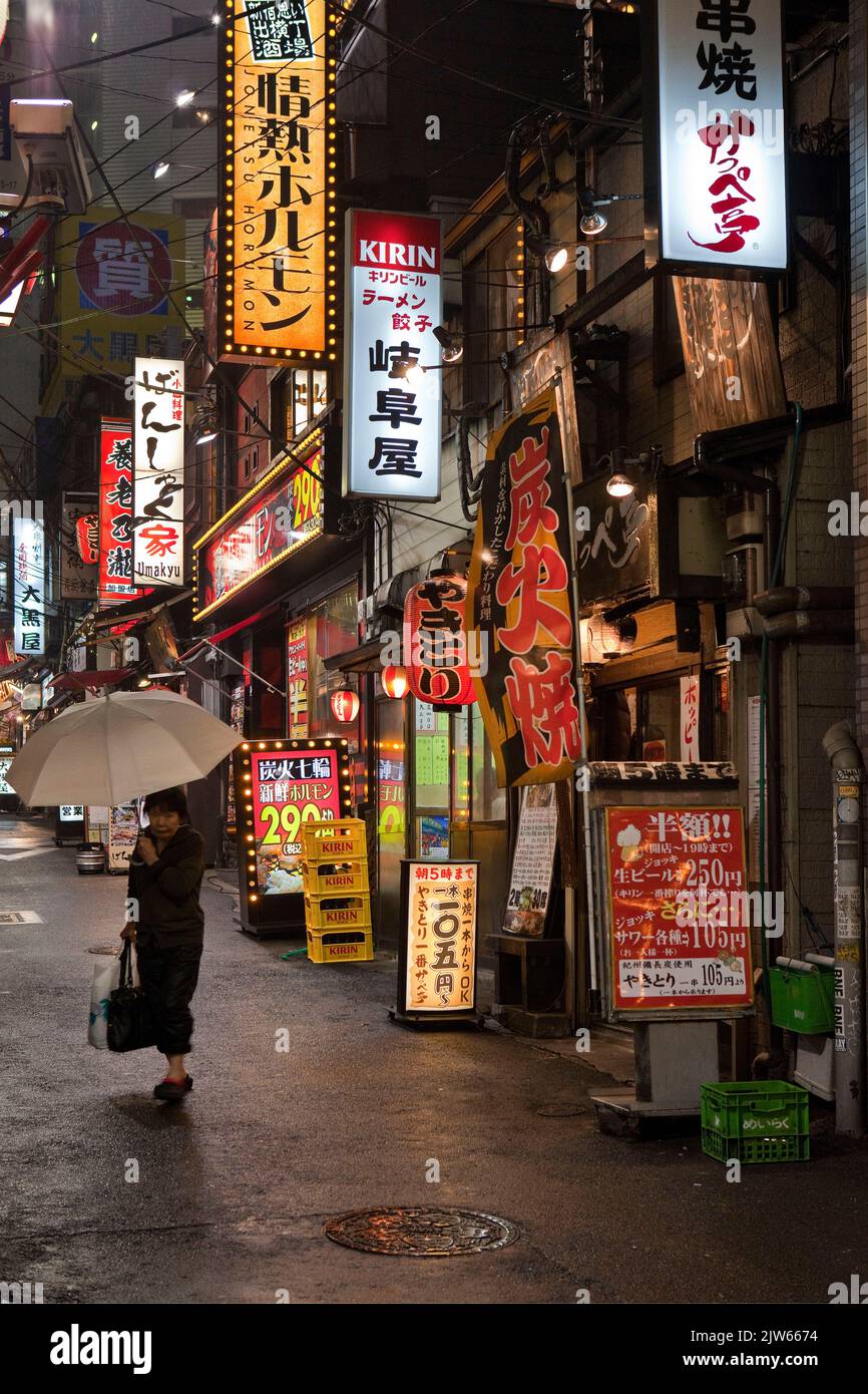 Restaurants signs glowing in a rainy alley street at night in Shinjuku, Tokyo, Japan Stock Photo
