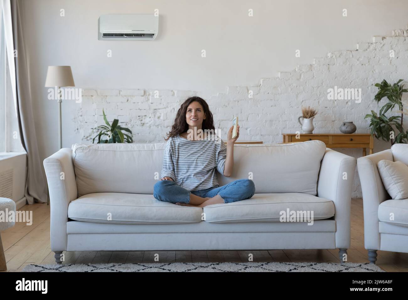 Attractive Hispanic woman holds remote controller turns on AC Stock ...