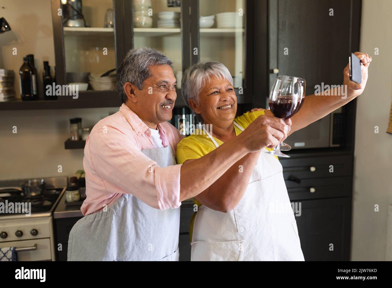 Senior african american couple drinking wine taking a selfie in kitchen ...
